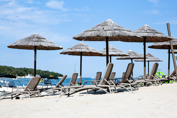 Armchairs with bamboo umbrellas and hammocks on sandy beach