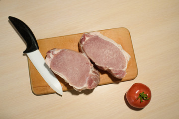 Sliced ​​pork meat on a board with tomato and white knife