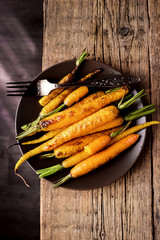 Baked Roasted Raw Freah Carrots with Olive Oil and Spices Lying on Plate Top View Horizontal Healthy Diet Organic Food Wooden Background Vertical