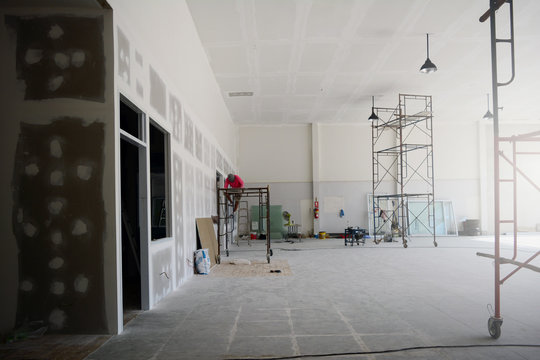 the iron scaffoldings on tile ground and the black lamp on  the ceiling with the labor while  renovation  the old office