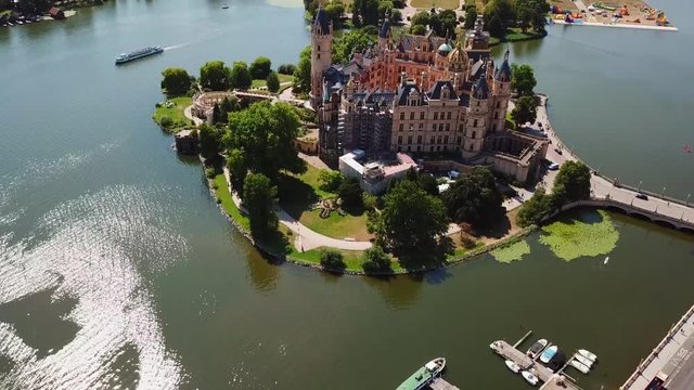 Aerial, orbit, drone shot, around the Schwerin Castle, above lake Schweriner see, on a sunny, summer day, in Germany