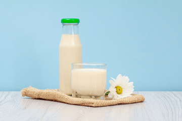 Bottle and glass of milk in blue background.
