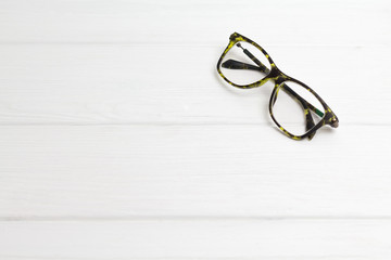 Modern black-green glasses on white wooden background. Minimalism. Front view