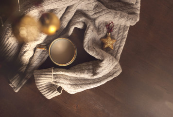 Winter homely scene. Warm knit sweater and cup of sweet cocoa  on wooden background.