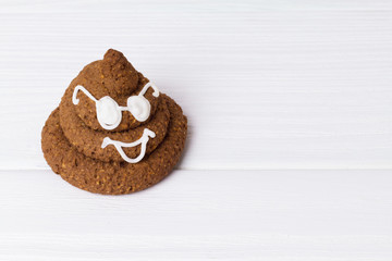 Funny poop emoji chocolate cookie with white decor and glasses. Cute food dessert. Free place for text. Copyspace.