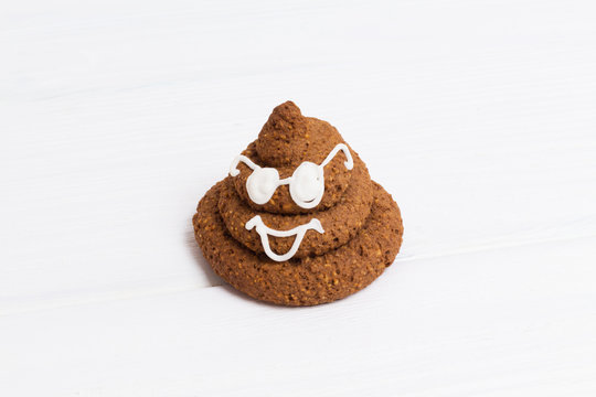 Funny poop emoji chocolate cookie with white decor and glasses. Cute food dessert. Free place for text. Copyspace.