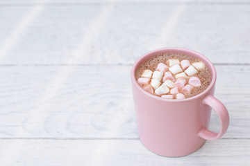 Hot chocolate with small pink and white marshmallows in a pink ceramic mug isolated on white...
