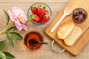 Traditional homemade strawberry jam in bowl, fresh berries with toast on wooden background.