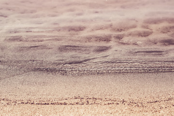 Fototapeta na wymiar Silent transparent waves and sandy beach close-up. Summer and travel concept