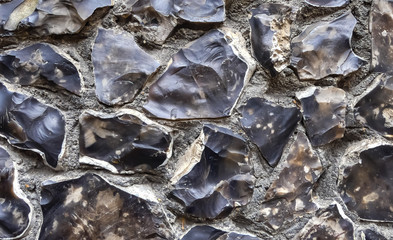 Close up of knap work flint rocks used to produce flushwork detail. Rendered into an exterior wall. Asymmetrical and individually made with imperfections, chips and tool marks. Landscape image.