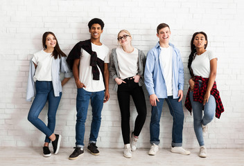 Group of stylish friends students posing over white wall