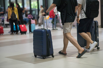 Traveler pulling suitcase in airport terminal.