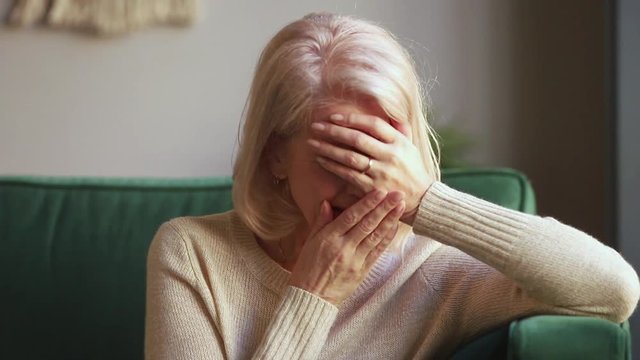 Desperate sad grieving old widow crying covering face with hands