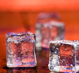 Melting ice cubes with droplets of water on a wooden background.