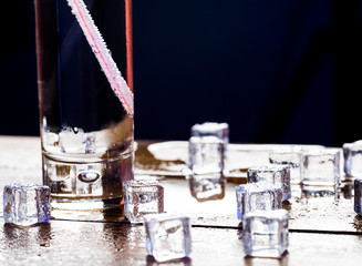 Melting cubes of transparent cold ice and a glass of soda with cocktail straw