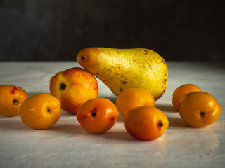 Large ripe pear, bald apricots and nectarines are on a bright table.