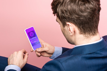 cropped view of businessman using smartphone with shopping app, isolated on pink