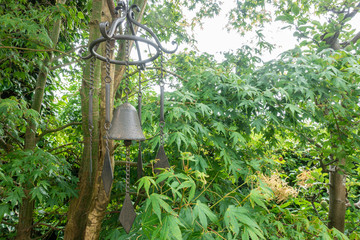 A wind chime garden ornament hanging from a tree in a garden