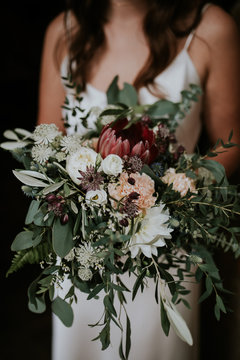 bride holding beautiful wild boho wedding bouquet with wild flowers