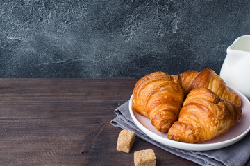 Freshly baked croissants on a plate, dark background, copy space.