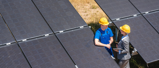 Two people standing amid solar cells in a power plant