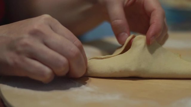 Cooking Tatar national dishes. Weaving and joining the sides of a triangular patty. Cooking baking flour