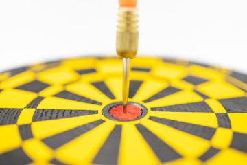 Game, Business, Planning and Target Concept.  Close up of  dart stab on center of black and yellow board on white background.