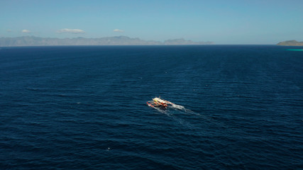 Aerial view tour boat in sea. Seascape blue sea and tropical islands. traditional Filipino wooden outrigger boat called a banca . Motorboat crossing ocean. Banca boat in the Philippines Palawan