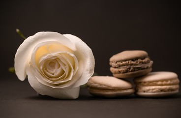 Fototapeta na wymiar Breakfast in muted tones. White and red roses in a vase chocolate candy cookies on a dark background