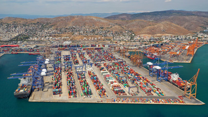 Aerial drone view of industrial cargo shipment and logistics port terminal with container trucks, ships and cranes