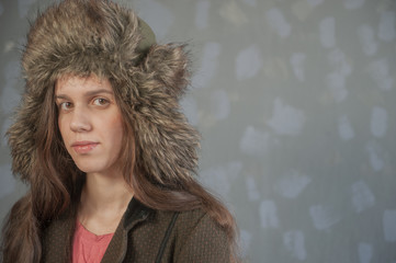 young girl with long hair in  faux fur hat in pink jacket and stylish coat posing in front of...
