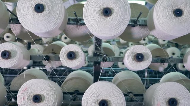 Tailoring loom with rotating sewing reels. Textile factory equipment.