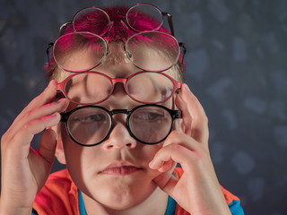 Photo of funny kid with many pairs of glasses on face
