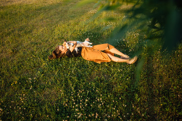 Happy beautiful young girl in dress with dog play in nature. Tinted and filtered photo. Modern youth lifestyle concept. man and animal together. little jack russell terrier
