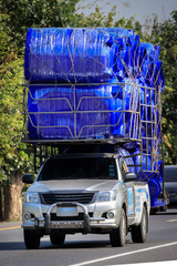 &Uuml;berladener Transporter mit blauen Tonnen auf einer &ouml;ffentlichen Stra&szlig;e in Thailand