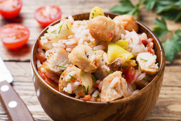 Stewed rice with chicken and vegetables in a wooden bowl.