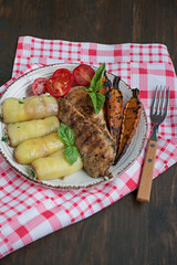 Grilled chicken fillet with baked vegetables. Wooden background.