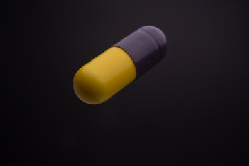 Floating or levitate black and yellow capsule pills in the thin air