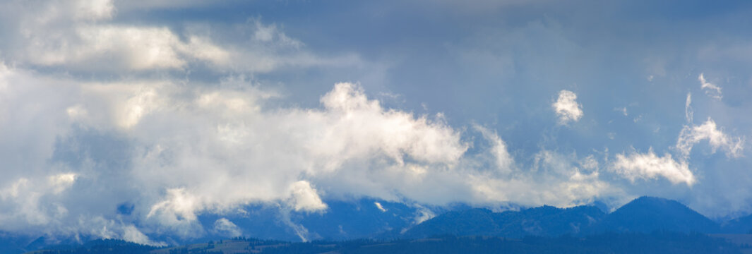 dramatic clouds above the mountain ridge.  panoramic nature background. dynamic side lit cloudscape