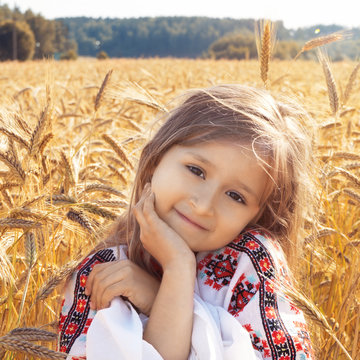 Little beautiful girl on the rye field in the national Russian embroidered shirt. Concept. Summer. Country landscape. Retro style. Vintage.