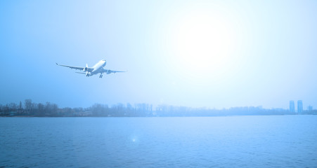 Plane over the river. Evening landscape and sun.