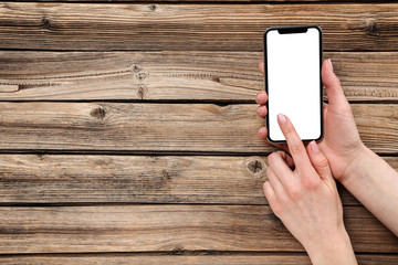 Smartphone in female hands on wooden background