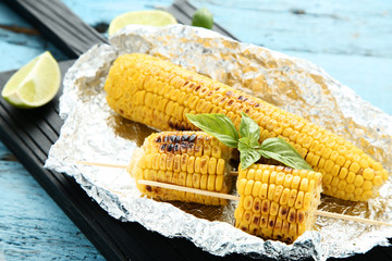Grilled corn with basil leafs on wooden table