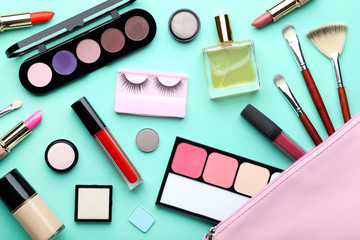 Different makeup cosmetics with perfume bottle on mint background