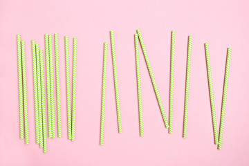 Green paper straws on pink background