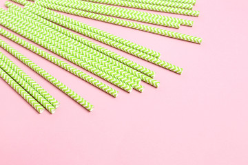 Green paper straws on pink background