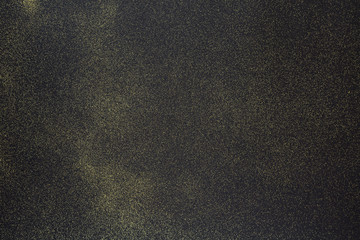 Obraz premium Golden glitter on the black background. Black glitter texture christmas abstract background. Top view, selective focus. 