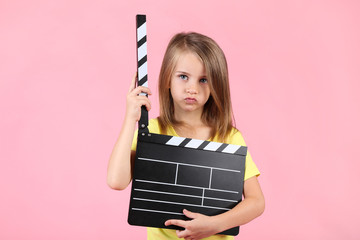Little girl with clapper board on pink background