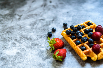 Clean background with negative space for healthy food and antioxidant fruits, and a waffle as junk food.