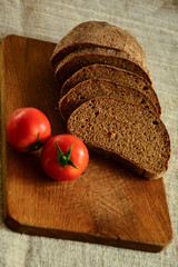  Freshly baked bread on a wooden cutting board with tomatoes